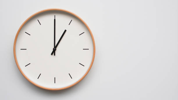 Picture of a simple clock on the wall, light wood. Time Set at 13.00/01.00