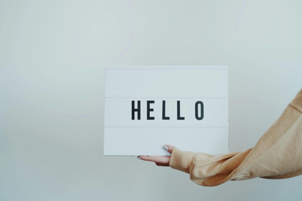 Image of a hand holding a small card which says hello. white background.
